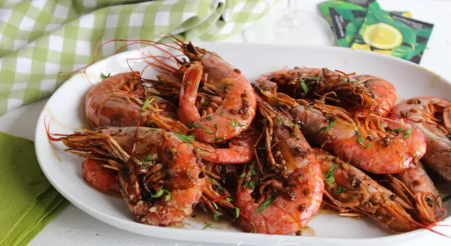 Plato de gambones al ajillo, jugosos y con perejil picado, listos para disfrutar.