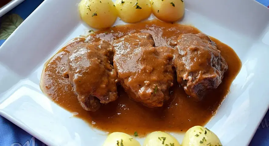 Carrilleras al vino tinto, tiernas y jugosas, bañadas en una rica salsa, acompañadas de patatas cocidas.