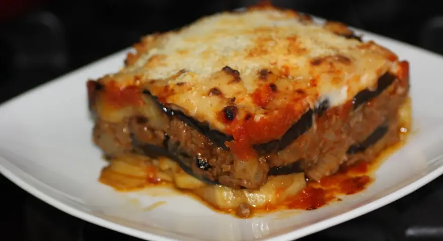 Porción de musaka casera con capas de berenjena, carne picada y salsa de tomate, gratinada con queso. ¡Una delicia de la musaka receta!