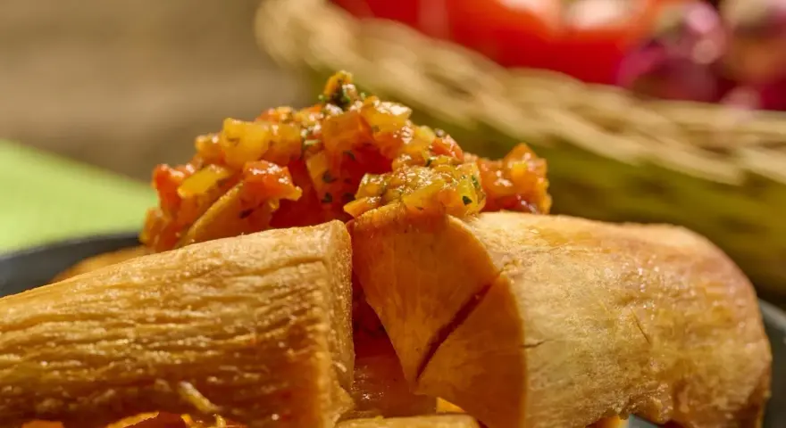 Crujiente yuca frita servida con una sabrosa salsa de tomate y cebolla.