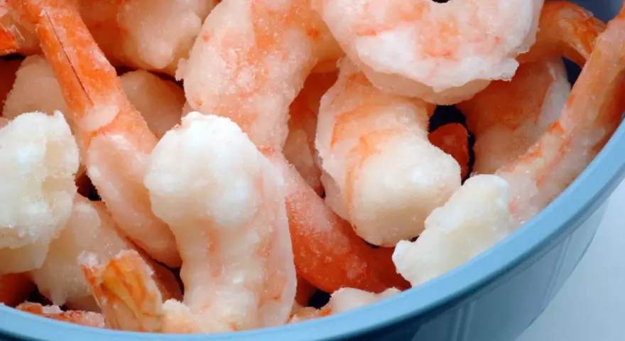 Langostinos cocidos congelados en un bol azul. Aprende cómo descongelar langostinos cocidos fácilmente para tus recetas.