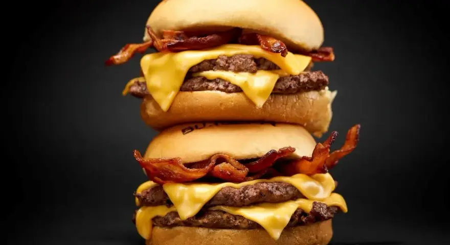 Dos hamburguesas caseras apiladas, con doble carne, queso fundido y crujiente tocino.