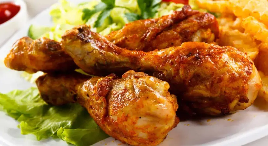 Crujientes muslos de pollo frito, acompañados de papas fritas, ensalada y tomate. ¡Un festín irresistible!