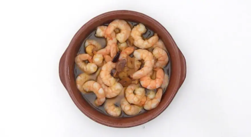 Gambas al pil pil burbujeantes en cazuela de barro, con ajo y aceite de oliva.