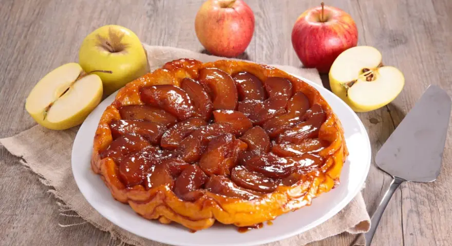 Deliciosa tarta tatin dorada y caramelizada, rodeada de manzanas frescas. Perfecta para compartir.