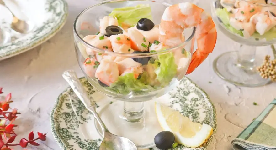 Delicioso cóctel de gambas servido en copa, con lechuga, aceitunas y un toque de limón. ¡Un clásico refrescante!