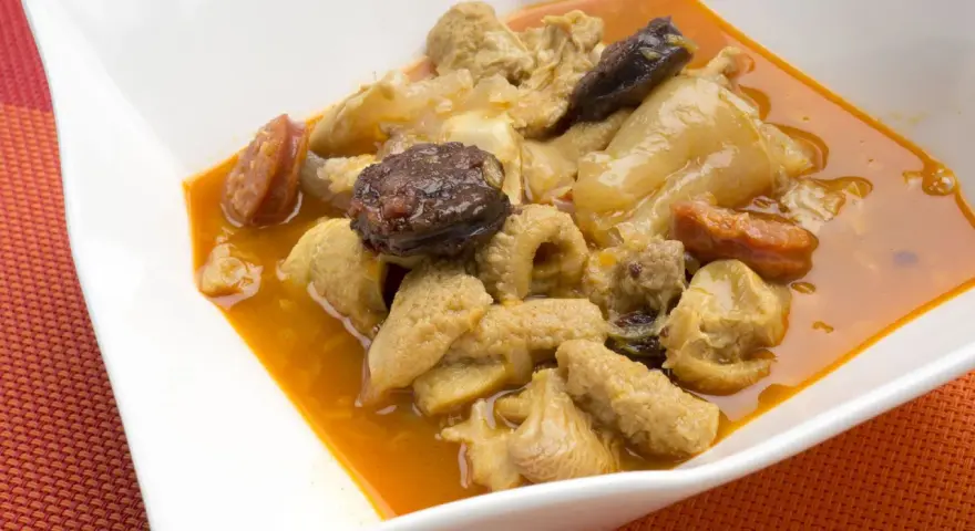 Un plato humeante de callos a la madrileña, con trozos de chorizo y morcilla en una rica salsa.