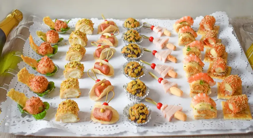Bandeja con aperitivos navideños originales: mini tacos, bolitas de pistacho, brochetas de jamón y gambas, y rollitos de salmón.