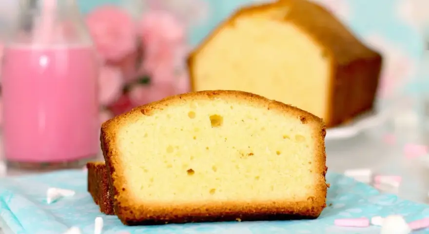 Rebanadas de bizcocho esponjoso, perfecto para tu próxima receta. Acompañado de un batido rosa y flores.