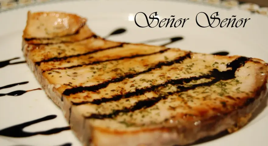 Un delicioso emperador a la plancha, con marcas de parrilla y un toque de hierbas, bañado en salsa oscura. ¡Un manjar digno de un Señor!