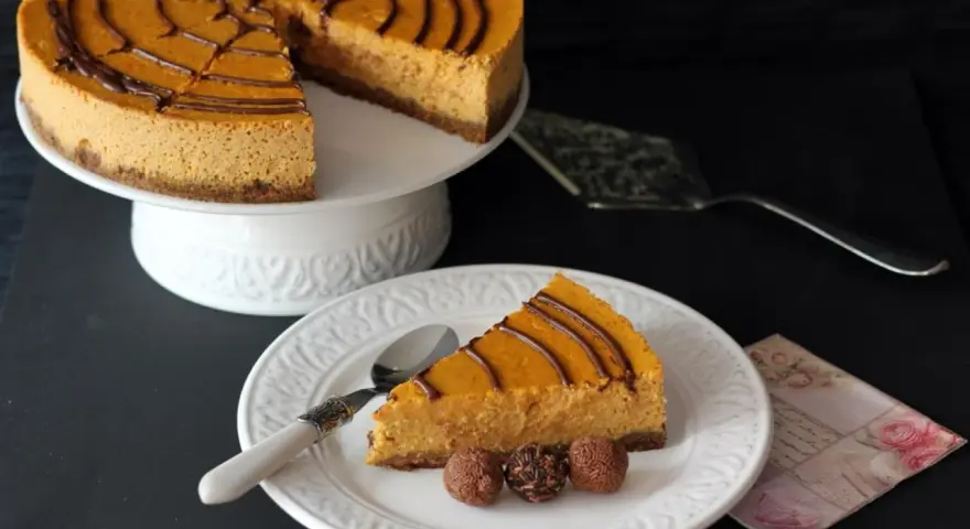 Deliciosa tarta de queso de calabaza con un toque de chocolate, servida en un plato blanco con tres trufas.