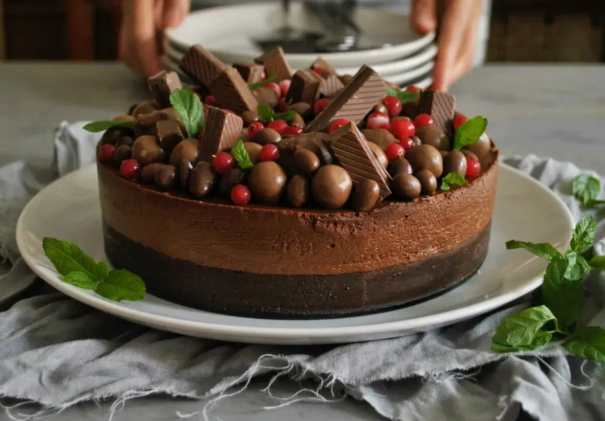 Deliciosa tarta de chocolate, cubierta con bombones, trozos de chocolate y frutos rojos.
