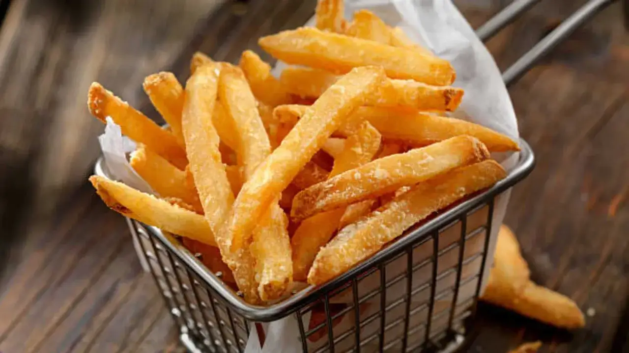 Cesta met&aacute;lica llena de crujientes patatas fritas doradas, listas para ser disfrutadas.