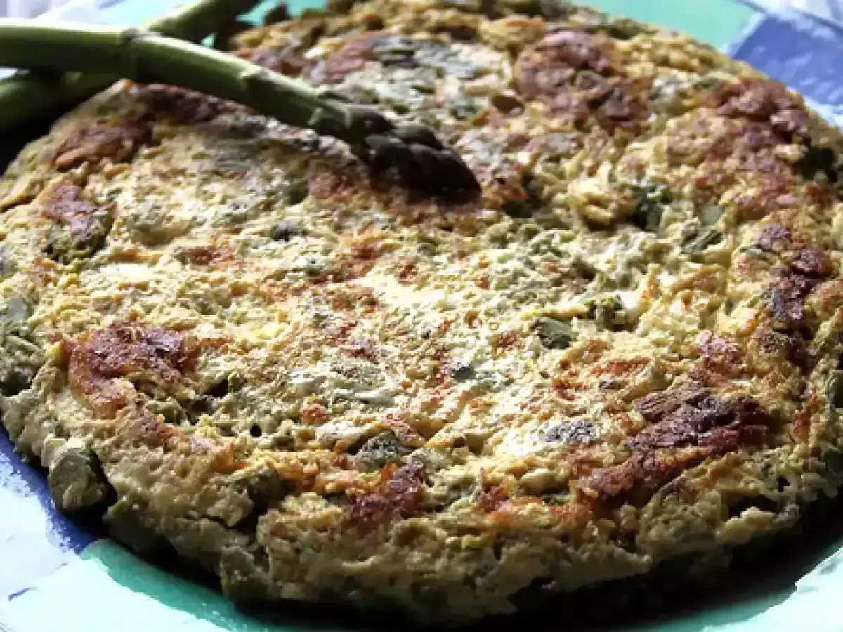 Tortilla de esparragos dorada y esponjosa, con esp&aacute;rragos frescos encima, lista para disfrutar.