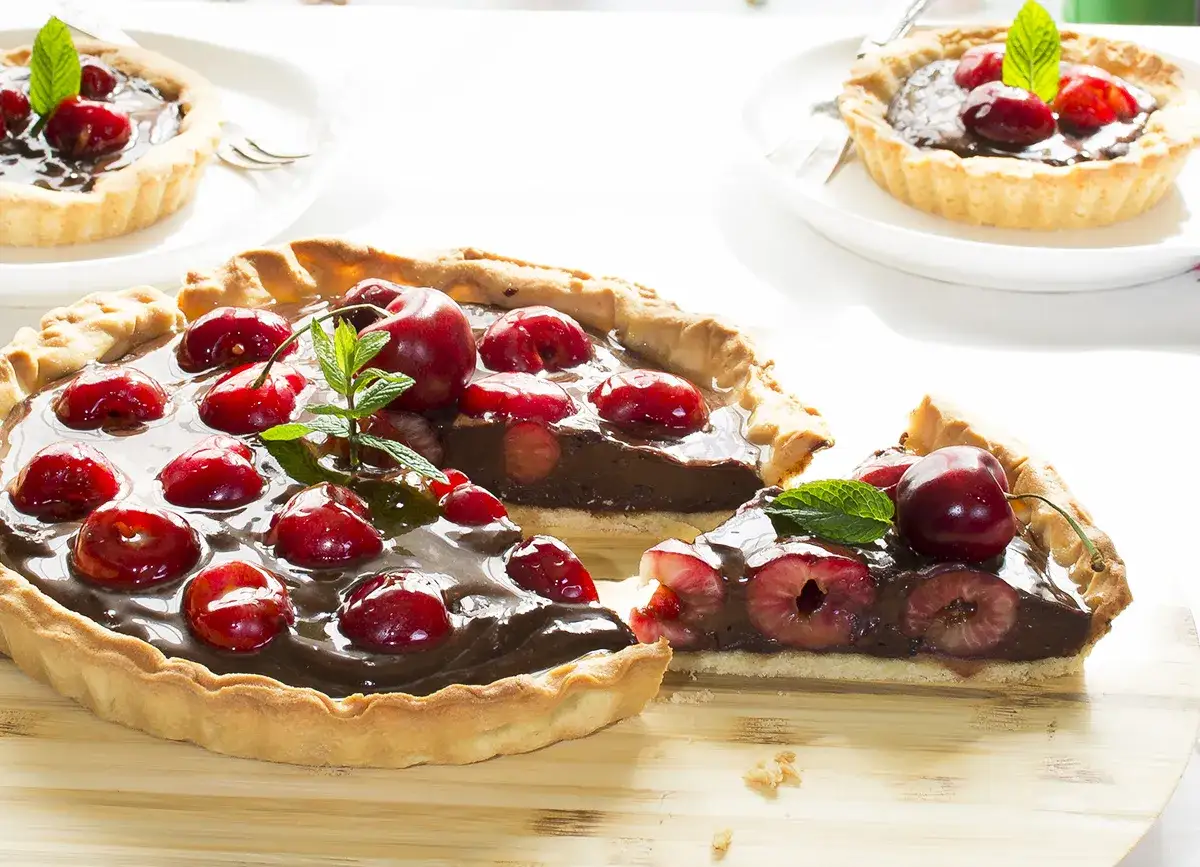 Deliciosos postres con cerezas, una tarta de chocolate y cerezas frescas, decorada con menta.