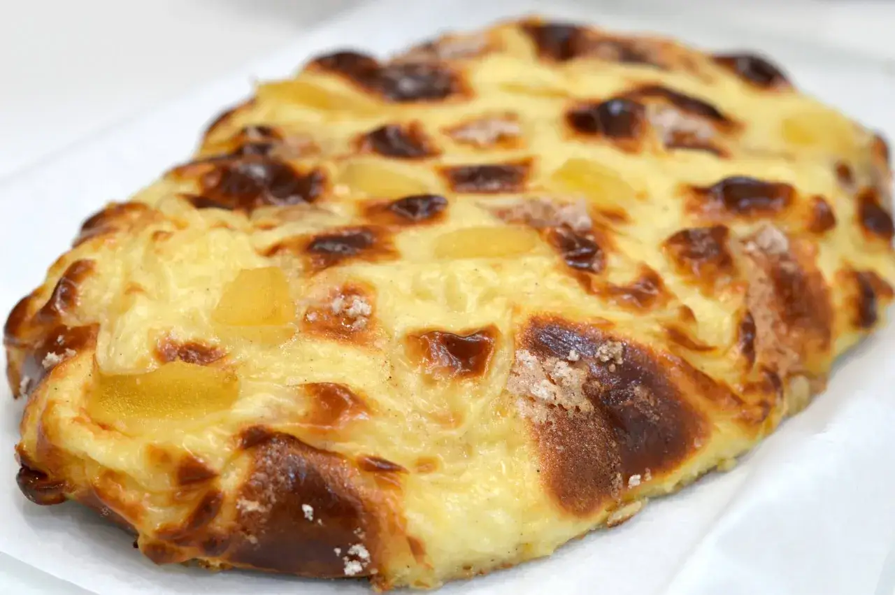 Deliciosa coca de Sant Joan con trozos de fruta confitada y un dorado perfecto, lista para celebrar.