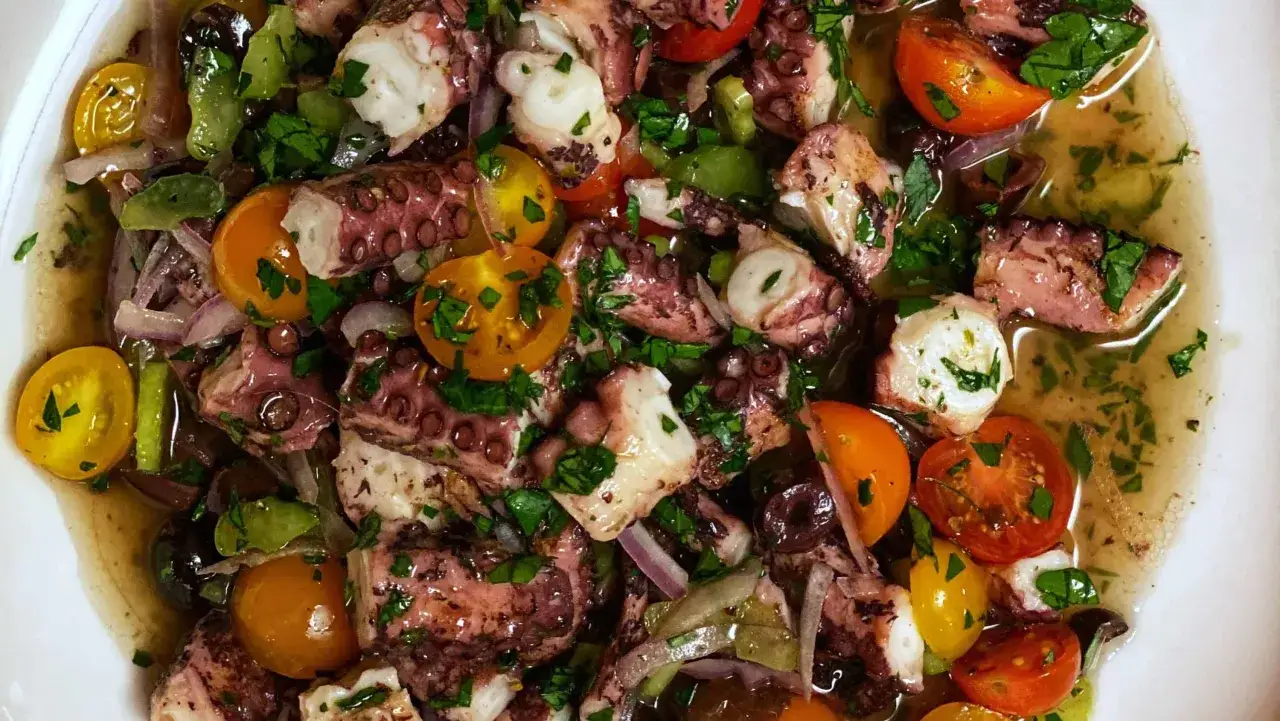 Ensalada de pulpo con tomates cherry, aceitunas y perejil. Un plato fresco y delicioso, ideal para recetas sanas con pulpo.