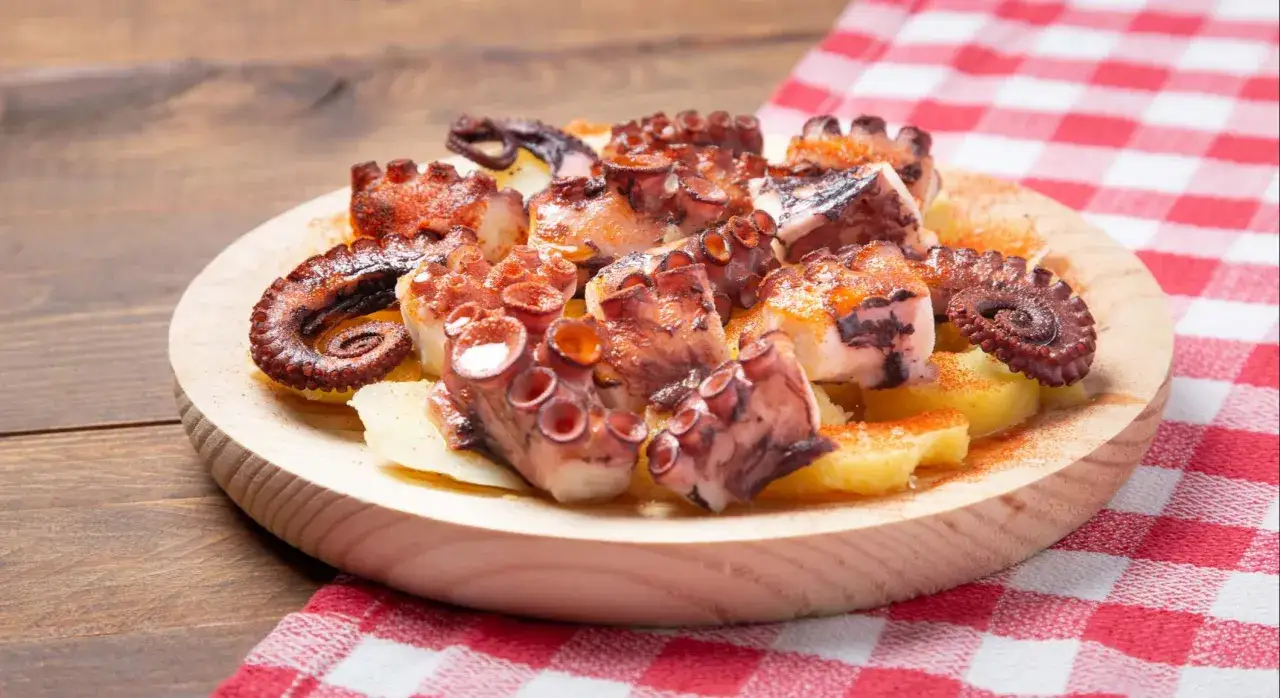 Pulpo cocido troceado y servido sobre patatas, espolvoreado con piment&oacute;n. Una forma deliciosa de como calentar el pulpo cocido.