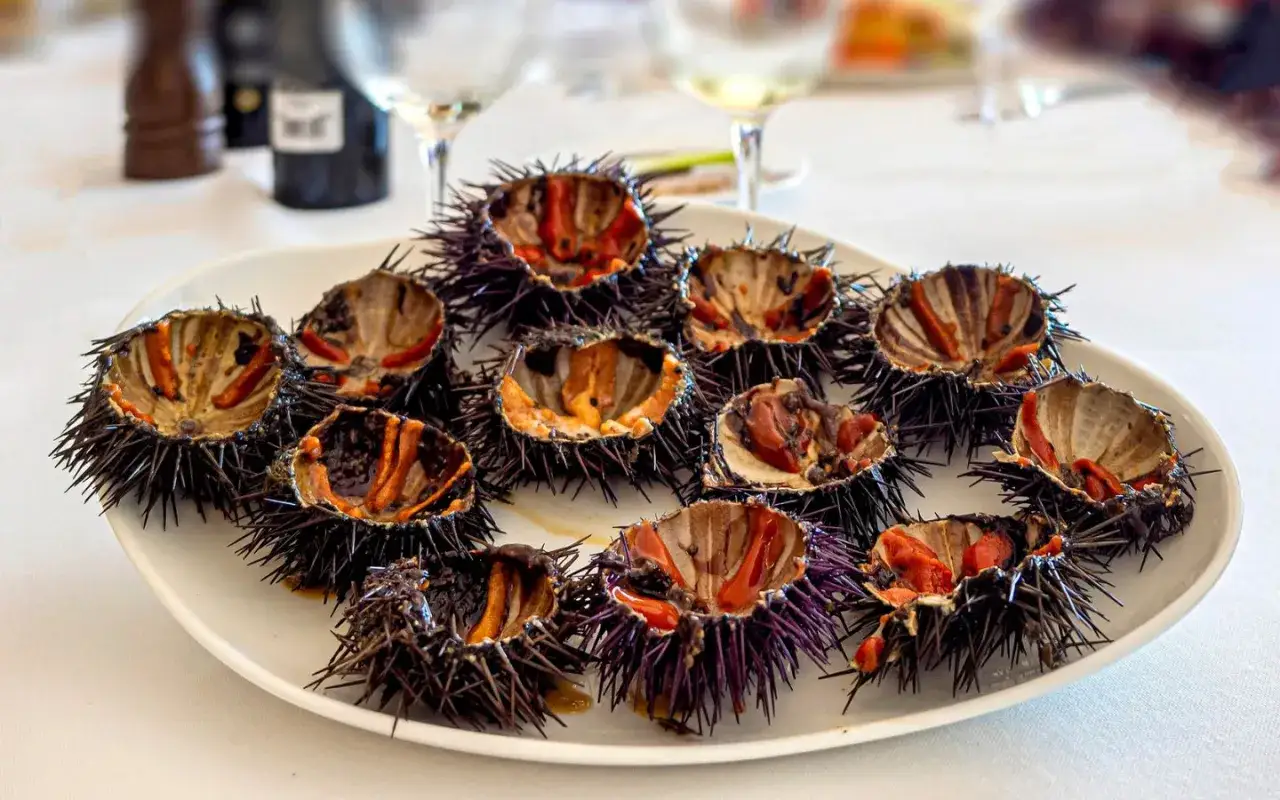 Plato con varios tipos de erizos de mar abiertos, mostrando su interior anaranjado y morado.