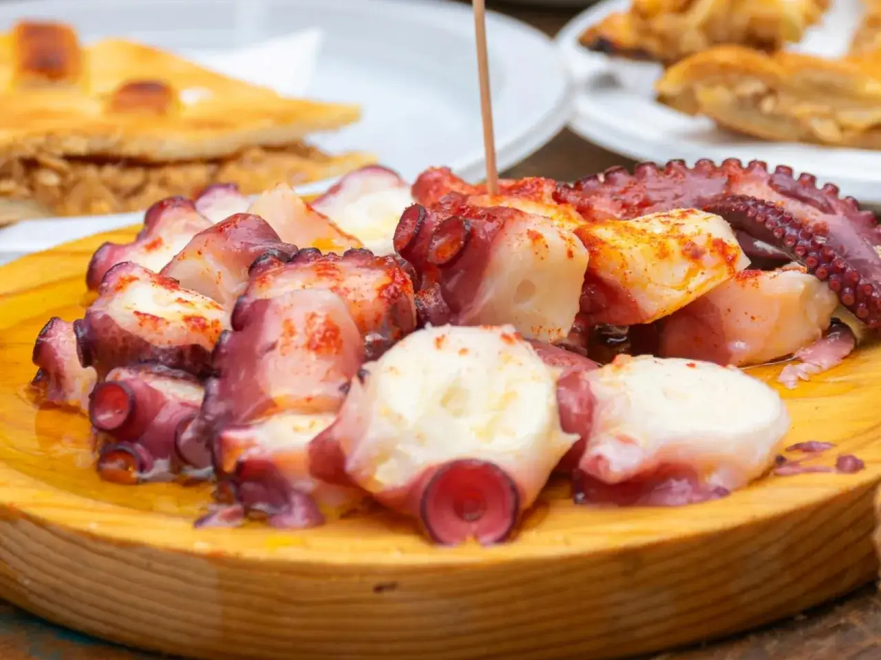 Pulpo a la gallega servido en plato de madera. El tiempo de cocci&oacute;n del pulpo por kilo es clave para esta delicia.