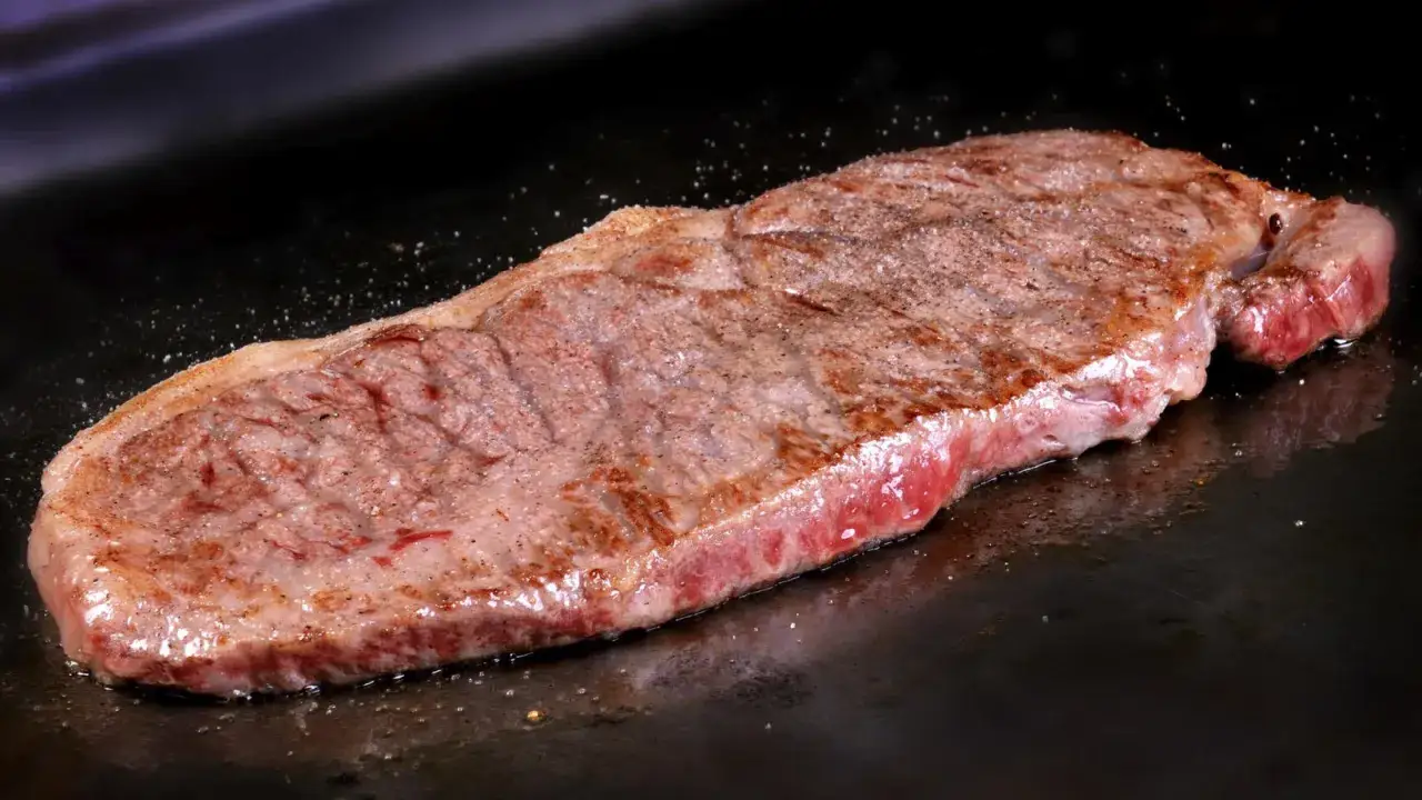 Un jugoso filete de ternera, perfectamente cocinado, chisporrotea en la plancha.