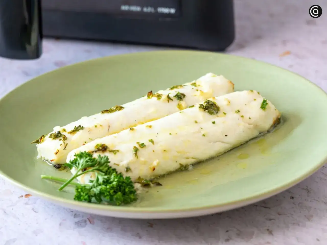 Dos filetes de merluza jugosa, reci&eacute;n hechos en airfryer, con hierbas frescas y aceite de oliva.