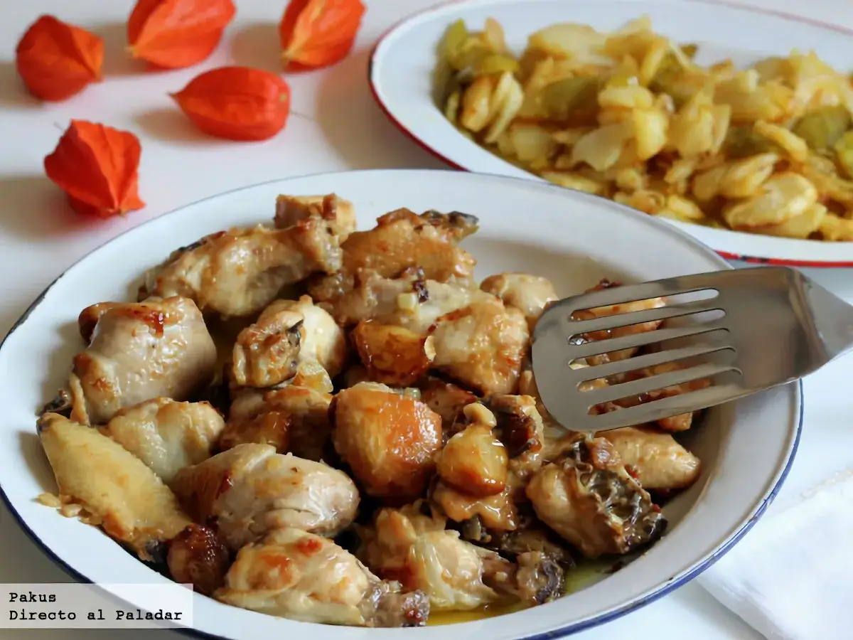Sabroso pollo al ajillo servido en un plato blanco, con trozos dorados y jugosos. Al fondo, otro plato con guarnici&oacute;n.
