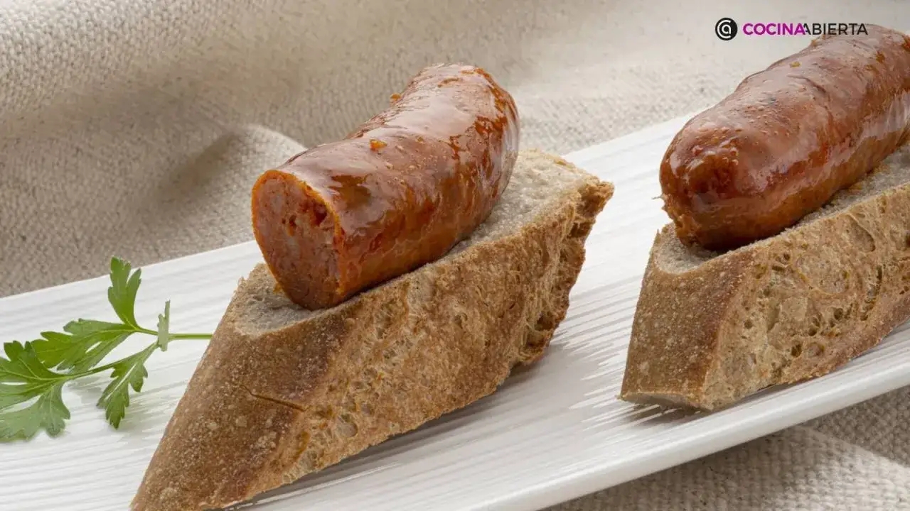 Chorizo a la sidra jugoso sobre pan rústico, decorado con perejil fresco. Un bocado delicioso.
