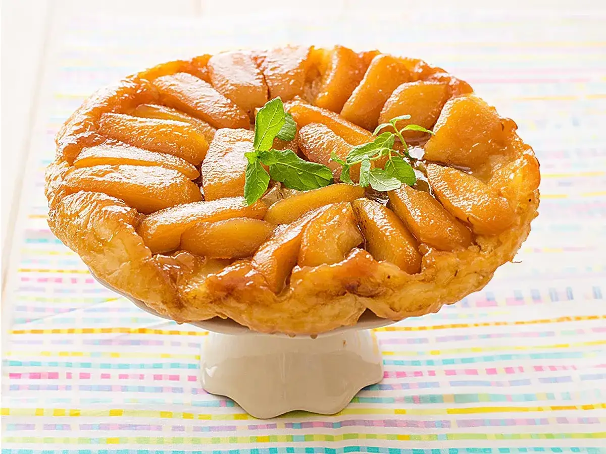 Tarta tatin dorada y caramelizada, con trozos de manzana tierna y una ramita de menta fresca. &iexcl;Un postre irresistible!