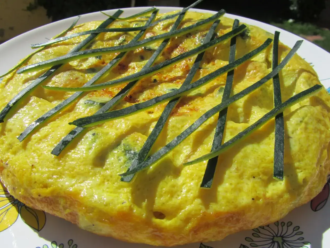 Tortilla de calabac&iacute;n dorada y esponjosa, decorada con finas tiras de calabac&iacute;n verde.