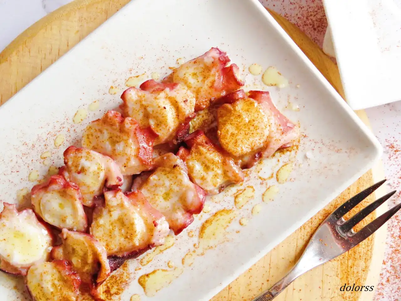 Pulpo cocido y troceado, servido en plato blanco con aceite y piment&oacute;n. &iexcl;Hay que descongelar el pulpo para cocerlo y disfrutar de este manjar!