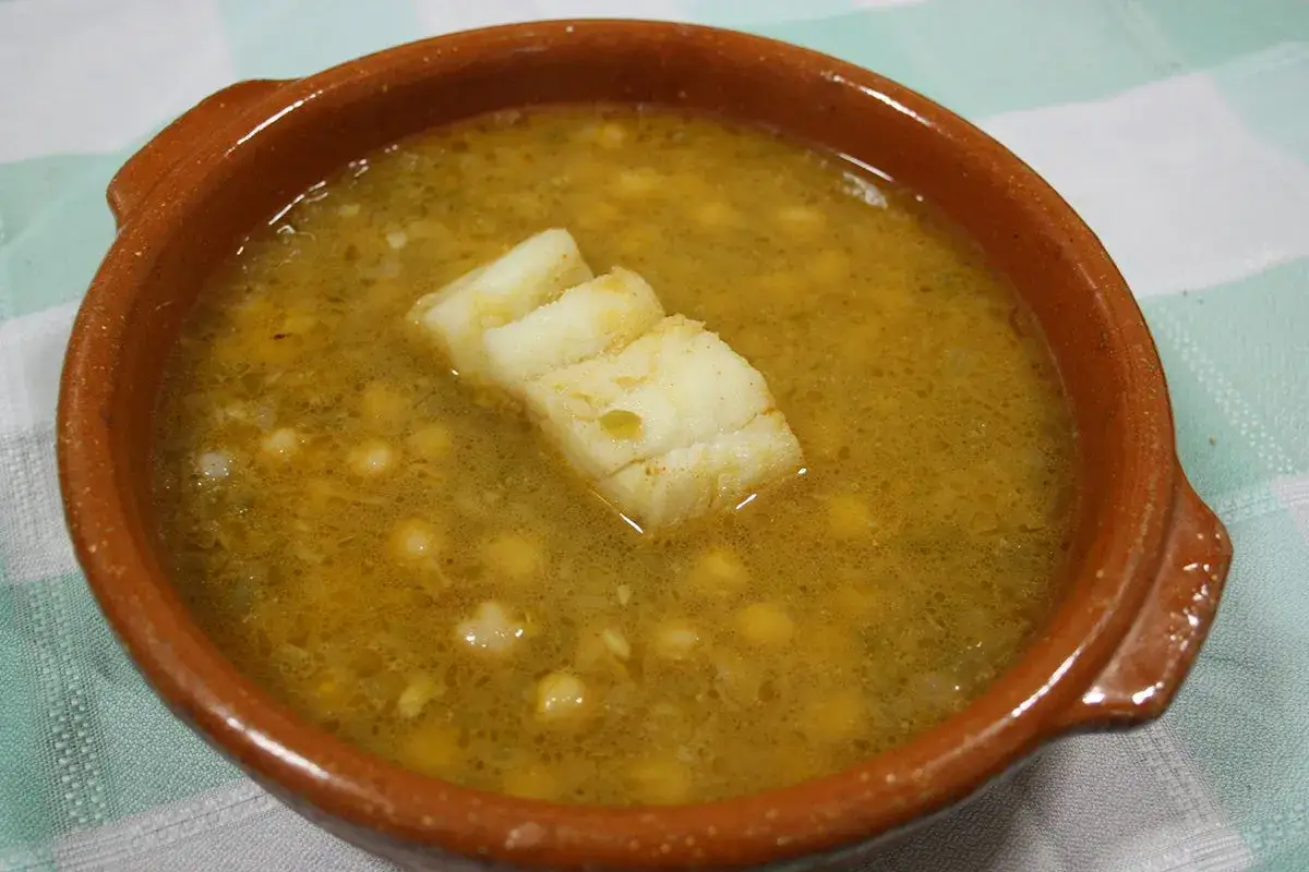 Un taz&oacute;n de barro con una deliciosa receta de garbanzos y trozos de pescado blanco.