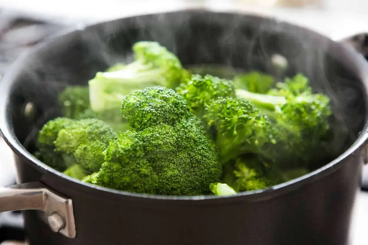 Br&oacute;coli verde vibrante cocin&aacute;ndose al vapor en una olla negra. El tiempo de cocci&oacute;n del br&oacute;coli en olla normal es clave para que quede perfecto.