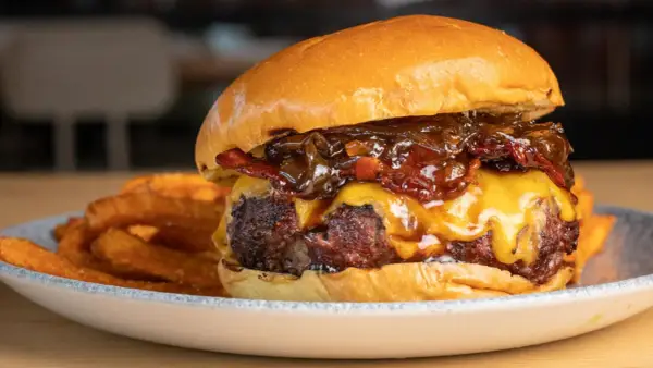 La mejor receta de hamburguesas caseras: jugosa carne, queso fundido, cebolla caramelizada y crujientes patatas fritas.