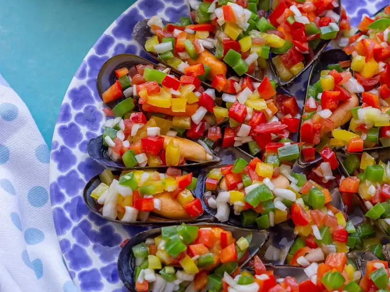 Mejillones a la vinagreta, cubiertos con una colorida mezcla de pimientos picados y cebolla.