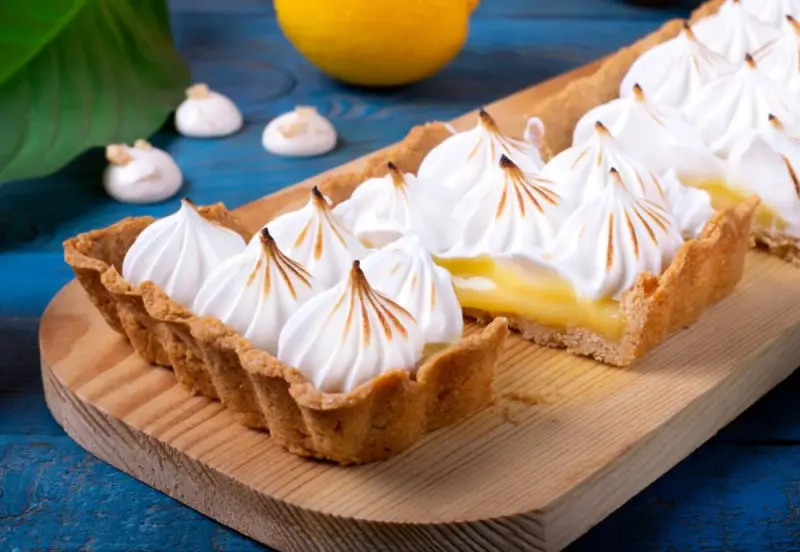 Tarta de limón con merengue suizo tostado, decorada con picos dorados.